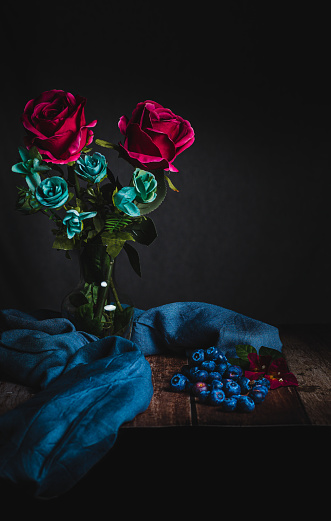 floral still life with blueberries, on a wooden table and blue cloth, copy space.