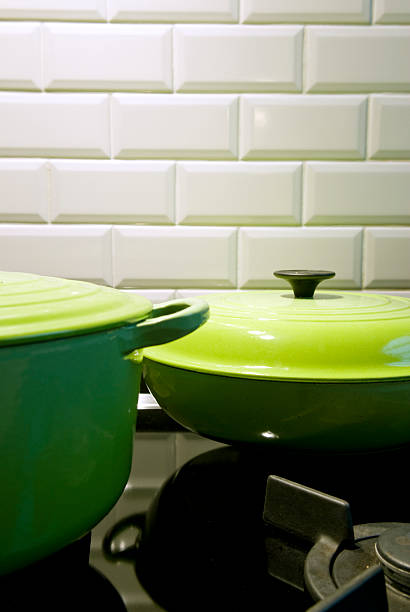 Two green cast iron cooking pots on a gas stove stock photo