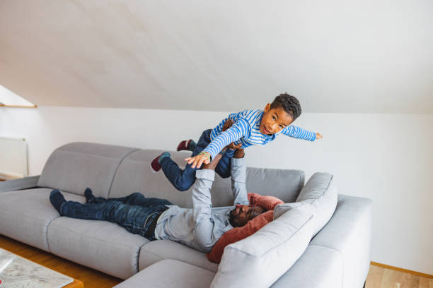 istock Black Male Lifting Up His Son On A Sofa 1458575464