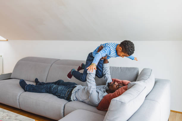 istock Black Male Lifting Up His Son On A Sofa 1458575468