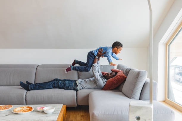 istock Black Male Lifting Up His Son On A Sofa 1458575472