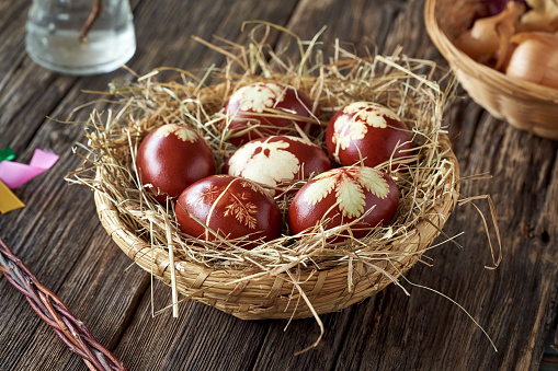 Easter eggs dyed with onion skins in a wicker basket on a wooden table in spring