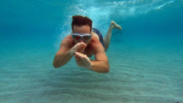 istock Man diving under the water surface. Swimming towards camera 1458577661