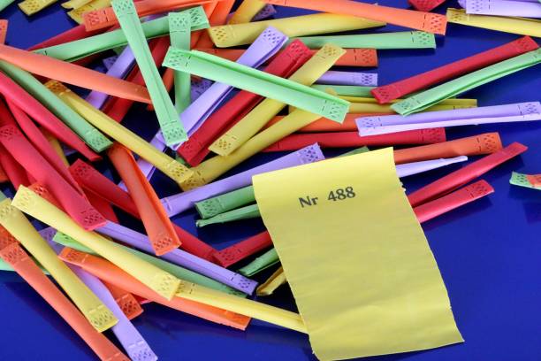 heap of colorful tombola tickets with a yellow winning number are lying on a blue reflection ground stock photo