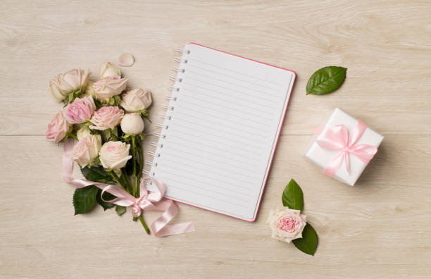 istock Notebook, gift box and rose flowers on wooden background, top view 1458579220