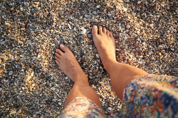 istock Female feet standing on pebbles at the beach, top view 1458580550