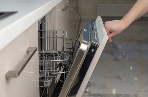 Opening and closing the dishwasher. woman's hand closes the dishwasher for washing dishes. Built-in dishwasher