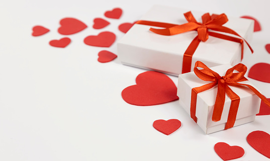 Gift box on the background of red hearts on a white background, with space for text. Postcard. banner.
