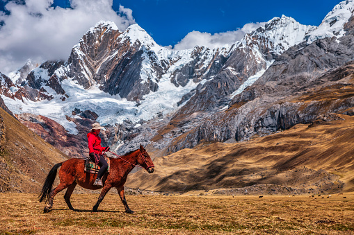 Young female tourist riding a horse in Peruvian Andes, Cordillera Huayhuash, South America. Andes Mountain Range is located in South America, running north to south along the western coast of the continent.It is a continual range of highlands along the western coast of South America.The Andes extend from north to south through seven South American countries: Argentina, Bolivia, Chile, Colombia, Ecuador, Peru, and Venezuela, and is the longest continental mountain range in the world.