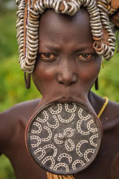 Portrait of woman with lip plate from Mursi tribe. Mursi tribe are probably the last groups in Africa amongst whom it is still the norm for women to wear large pottery or wooden discs or ‘plates’ in their lower lips.