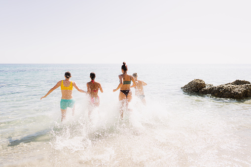 Photo of a couple of female friends having fun, running, splashing and enjoying their  summer vacation by the sea
