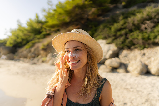 Mujer joven aplicándose protector solar en la playa photo