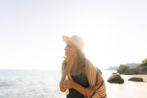 istock Young woman applying sunscreen at the beach 1458599582