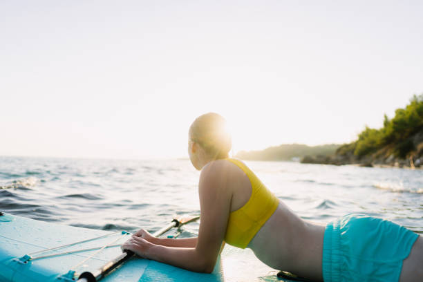 istock Young woman stand up paddling on the beach 1458599700