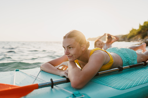 Young woman stand up paddling on the beach