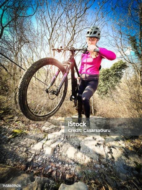 A Young Woman Carrying A Mountain Bike Uphill Stock Photo - Download Image Now - Extreme Sports, Pink Color, 20-29 Years