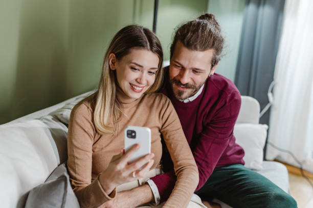 istock Young couple embracing at home and using smart phone 1458602337