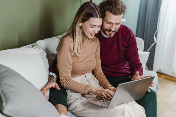 istock Cheerful couple using laptop at home and surfing the Net 1458602367