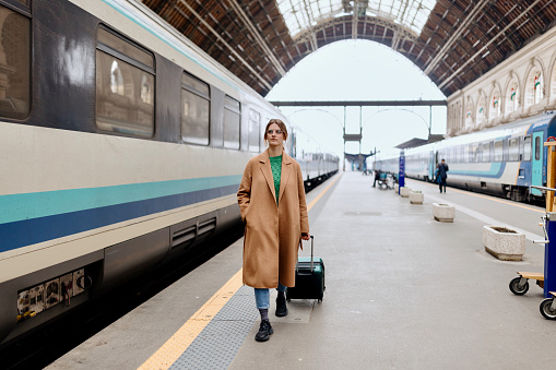 Young and beautiful woman walking with suitcase at the  railway station near the train.