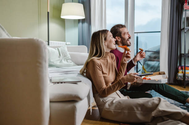 Couple eating pizza and watching TV stock photo