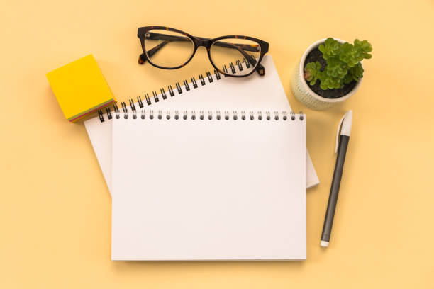istock notepad page, glasses, pen, stationery on yellow background. conceptual image 1458608856