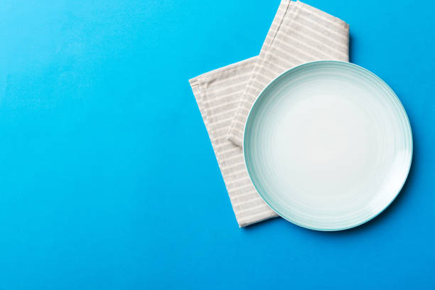 istock Top view on colored background empty round blue plate on tablecloth for food. Empty dish on napkin with space for your design 1458609311