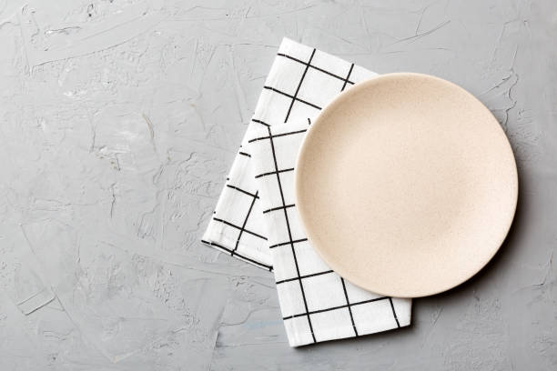 istock Top view on colored background empty round white plate on tablecloth for food. Empty dish on napkin with space for your design 1458609321