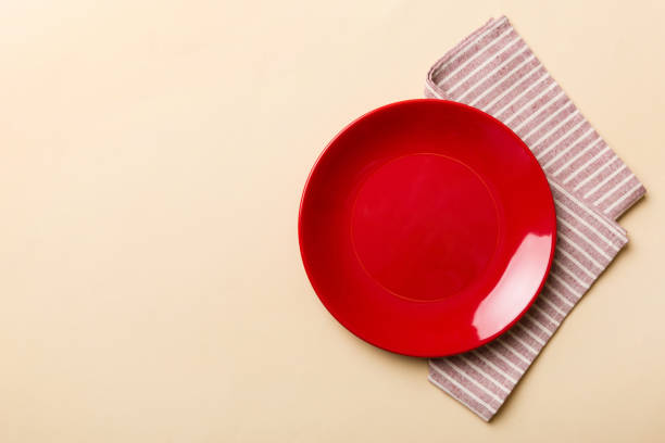istock Top view on colored background empty round red plate on tablecloth for food. Empty dish on napkin with space for your design 1458609325
