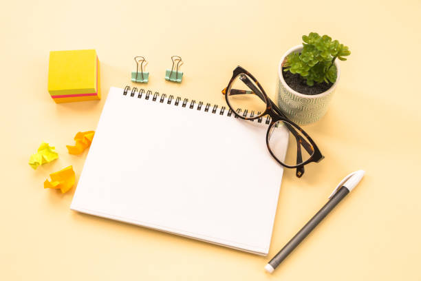 istock notepad page, glasses, pen, stationery on yellow background. conceptual image 1458609406