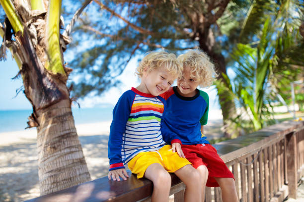 Kids play at tropical beach. Children playing at sea on family summer vacation on exotic island. Little boy in sun protection wear at swimming pool of resort. Holiday with young child. Kid at ocean.