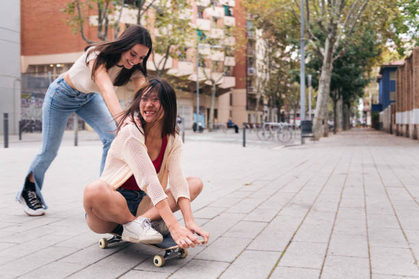 istock women laughing and playing with a skateboard 1458613538