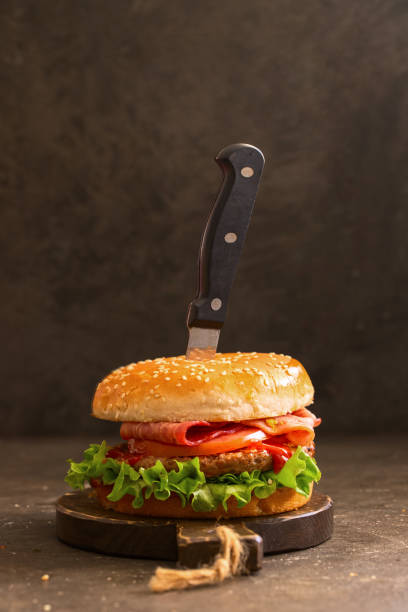istock Delicious hamburger with beef, bacon, cheese and vegetables on  wooden cut board. 1458613689