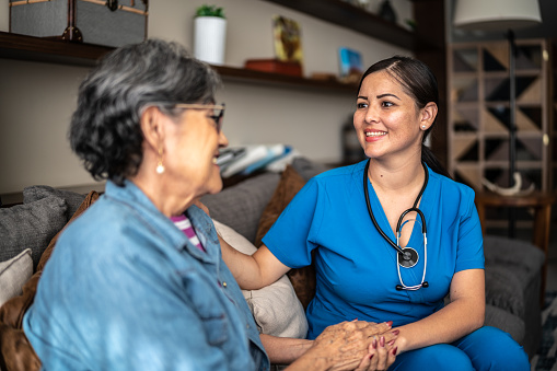 Young nurse woman talking with senior patient woman at nursing home
