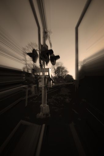 special effects, sepia toned view of the warning equipment like lights and gates at a railroad crossing in the downtown district of a village on Long Island, New York State