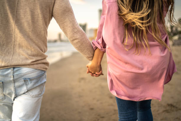 istock Couple holding hands while walking on the beach 1458617256