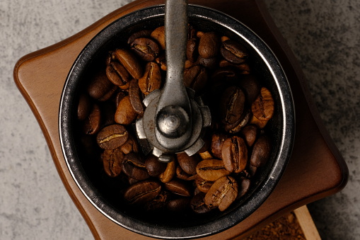 High angle composition of  coffee beans and vintage coffee grinder on abstract background, space for text