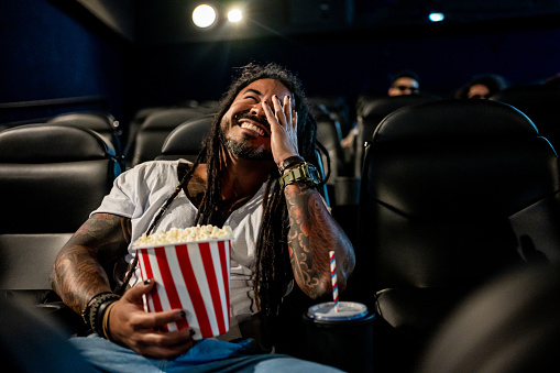 Man with dreadlocks watching movie at cinema