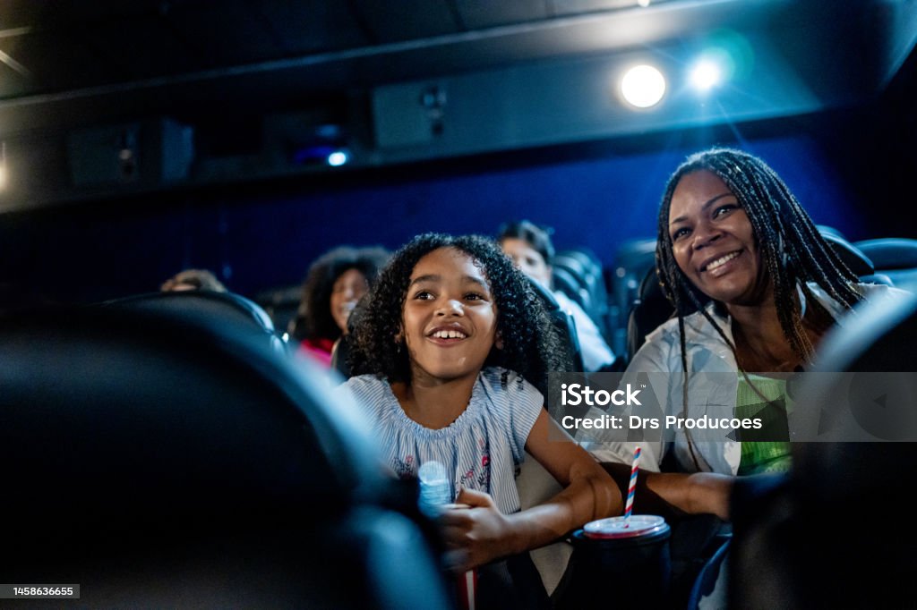 Mother and daughter smiling at the cinema Movie Theater Stock Photo