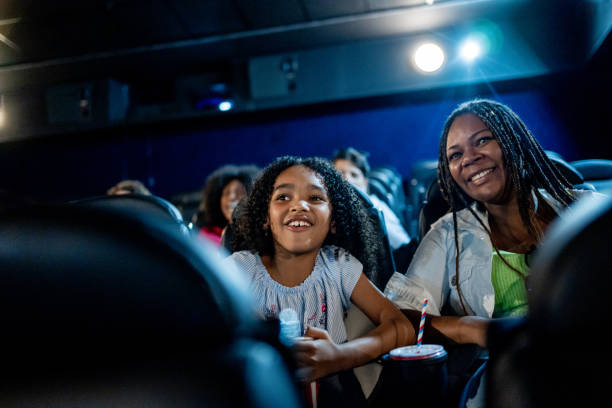 Mother and daughter smiling at the cinema Mother and daughter smiling at the cinema cinematography stock pictures, royalty-free photos & images