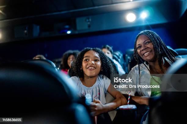 Mother And Daughter Smiling At The Cinema Stock Photo - Download Image Now - Movie Theater, Movie, Film Industry