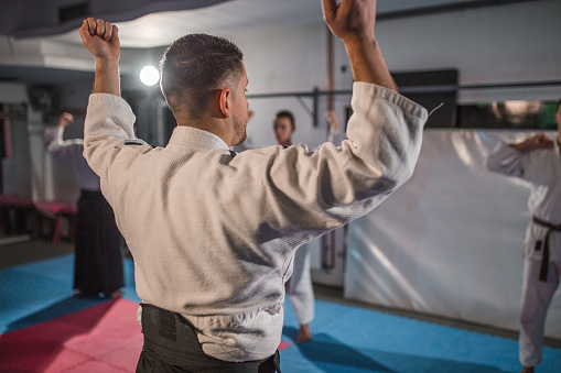 An aikido coach demonstrates warm-up exercises to a small group of young fighters