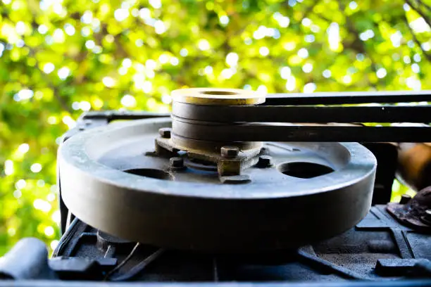 Driven pulley of a walk-behind tractor with two belts close-up on a blurred background. Small Tractor Engine for Garden Tillage