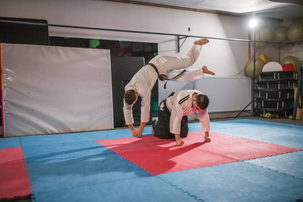 istock A young fighter practices an aikido fall and performs a forward flip exercise over his aikido master 1458650644