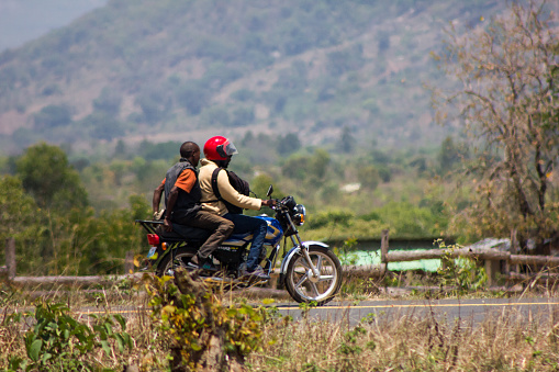 Mozambique - October 10, 2019: Riding to the Next Village: A Motorcycle Taxi (Boda-boda) on a Rural African Landscape