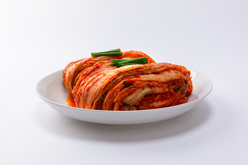 Korean kimchi. Korean traditional cabbage kimchi on white plate. White background, frontal closeup.