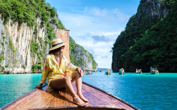 Asian women in front of a longtail boat at Kho Phi Phi Thailand at Pileh Lagoon with turqouse water Asian women in front of a longtail boat at Kho Phi Phi Thailand, women in front of a boat at Pileh Lagoon with turqouse colored ocean kao sok national park stock pictures, royalty-free photos & images