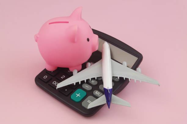 Airplane model, piggy bank and calculator on pink stock photo