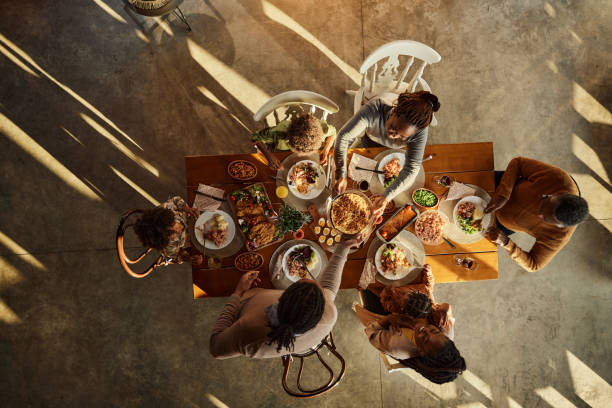 Above view of black extended family having lunch at dining table. High angle view of African American multi-generation family having a meal at dining table. Copy space. black people eating stock pictures, royalty-free photos & images