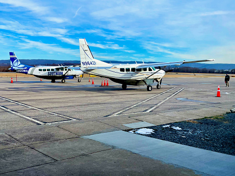 Morgantown, West Virginia, USA - January 16, 2023: A marshaller stands ready to direct one of two Southern Airways Express Cessna 208 Caravan aircraft to taxi for take-off outside the passenger terminal at Morgantown Municipal Airport’s Walter J. Hart Field.