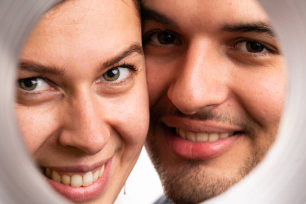 Close-up of adult boyfriend and girlfriend couple portrait faces through round circle frame isolated on white studio background